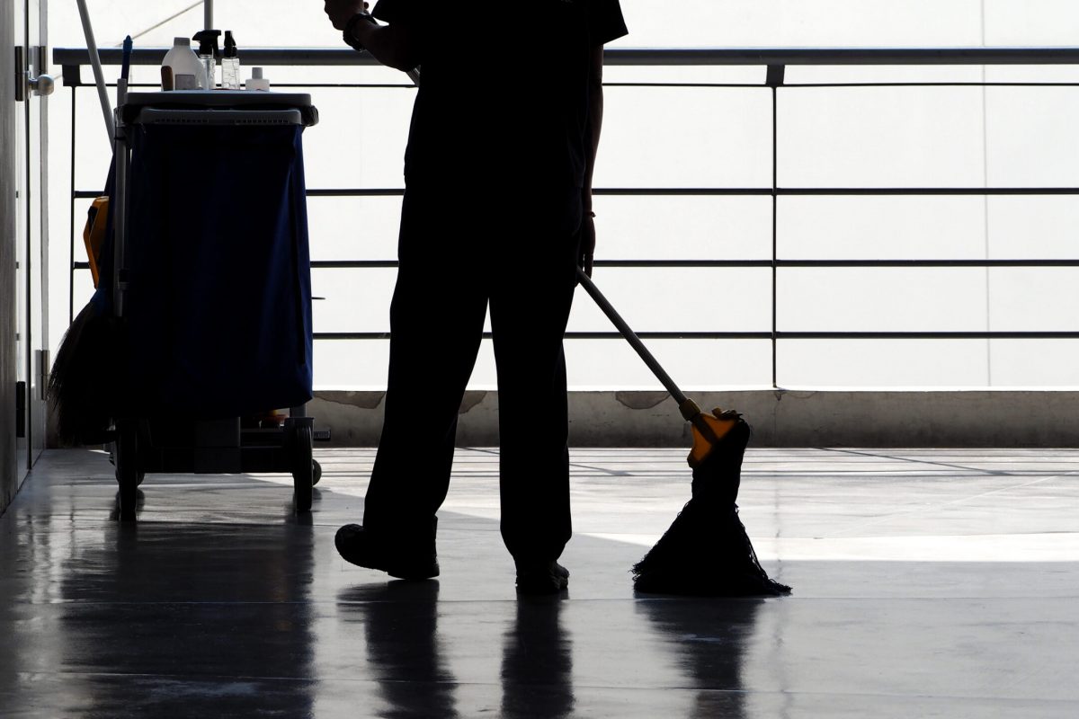 Silhouette image of cleaning service people sweeping floor with mop and other equipment on trolley.